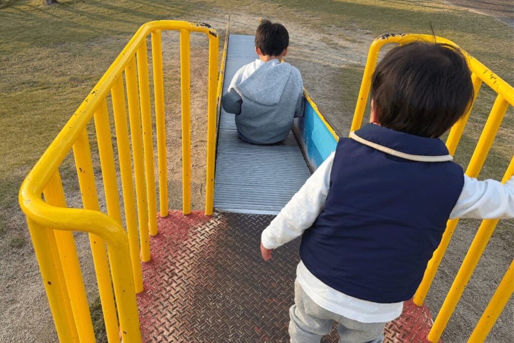 ローラーすべり台の前で少し尻込みする1歳児(2025年11月)