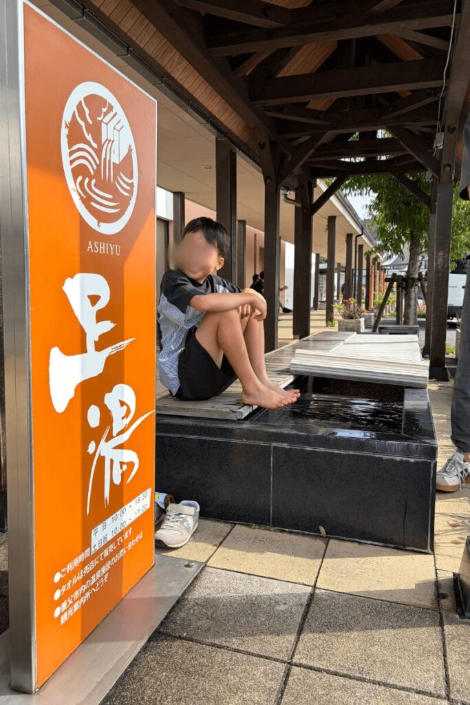 道の駅ようかの足湯に足を入れて、熱さに驚く長男