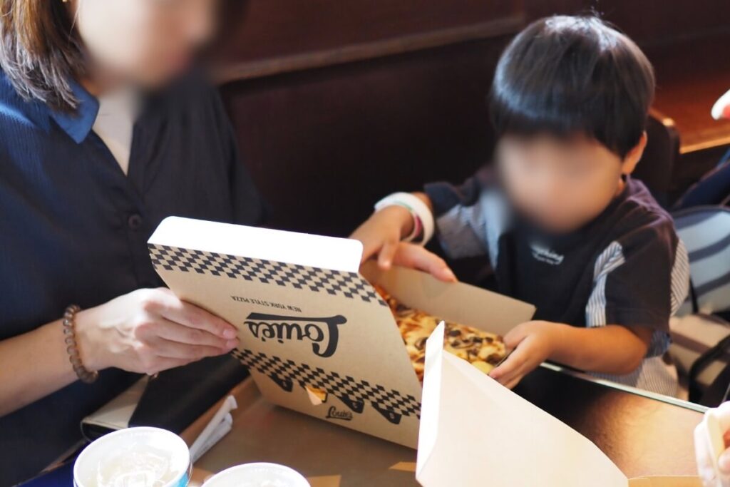 ルイズ N.Y. ピザパーラーのピザの箱を開ける2歳の次男